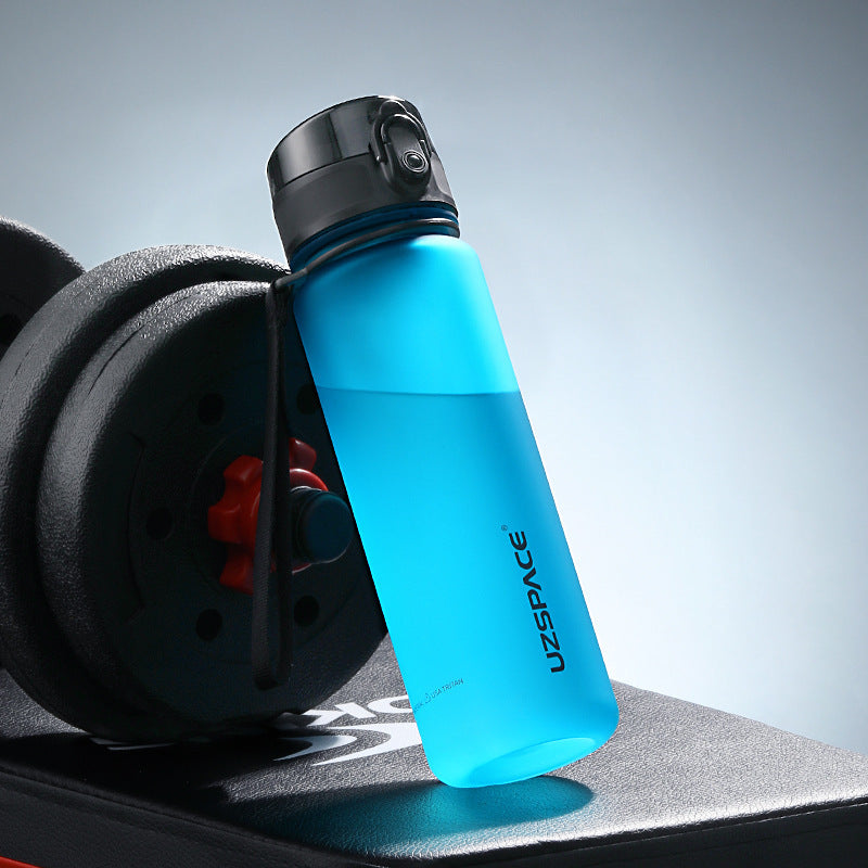 Blue water bottle with black cap on a black surface, featuring the UZSPACE brand.